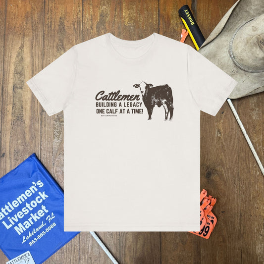 White t-shirt with a graphic and text on a wooden surface with related items.